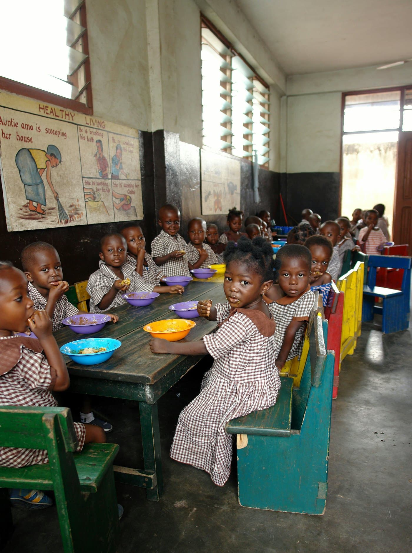 Young children eating a meal together at small tables