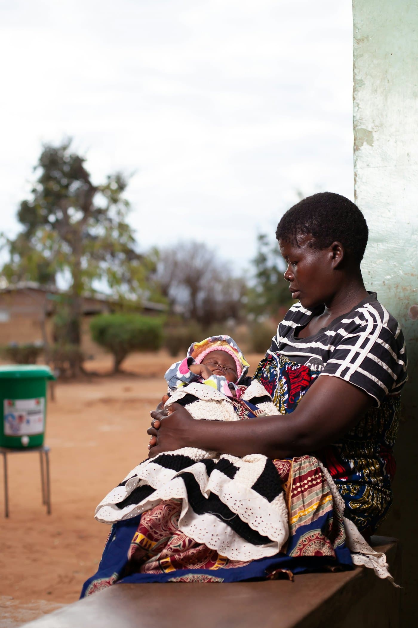 A mother sitting outdoors holding her baby