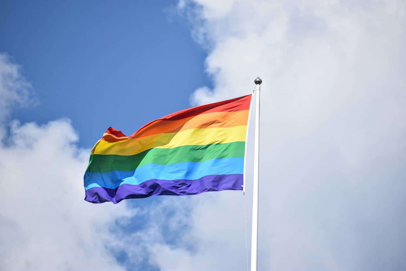 A rainbow Pride flag flying high among the clouds