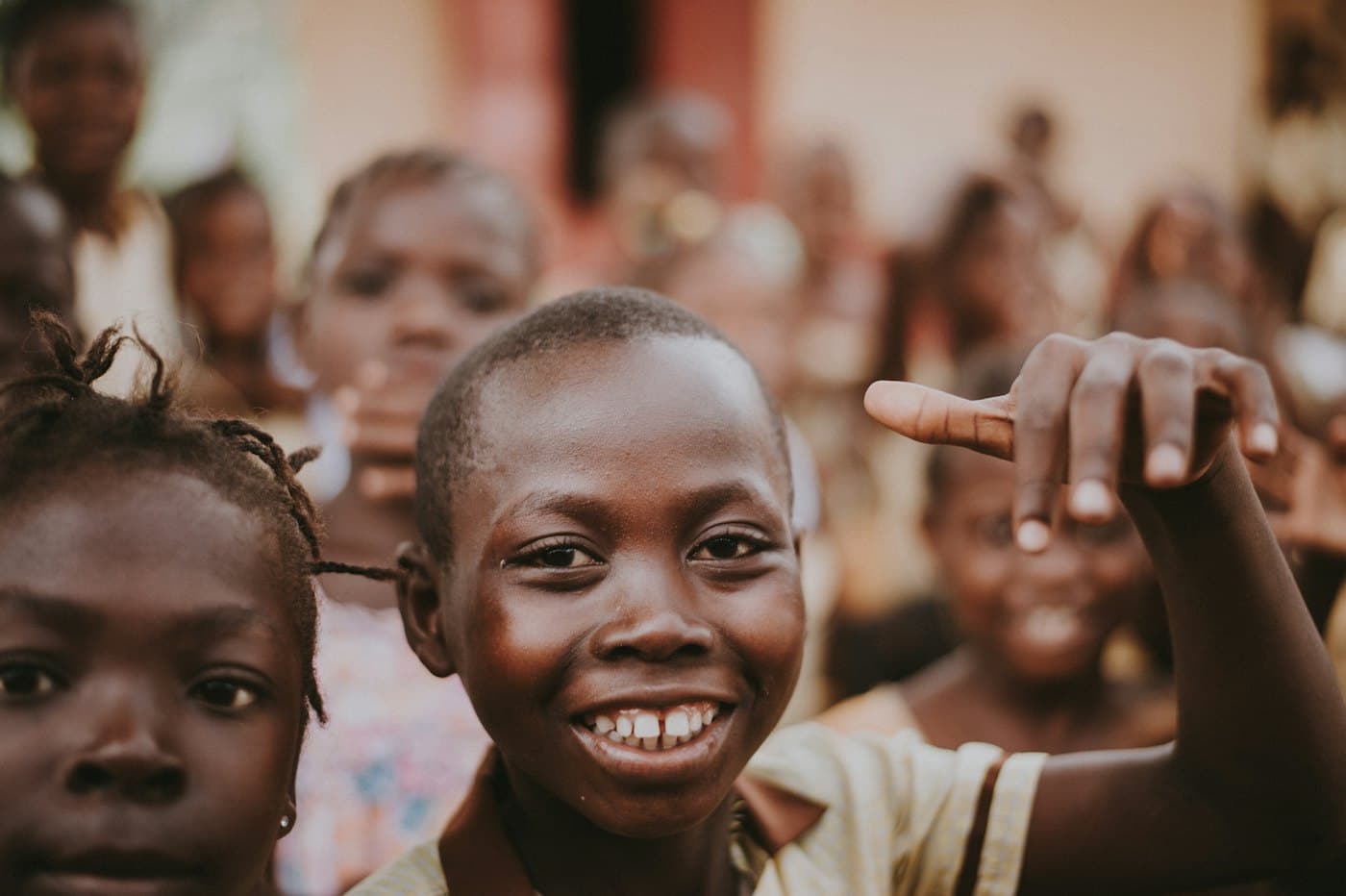 A boy smiling at the camera with other children behind him