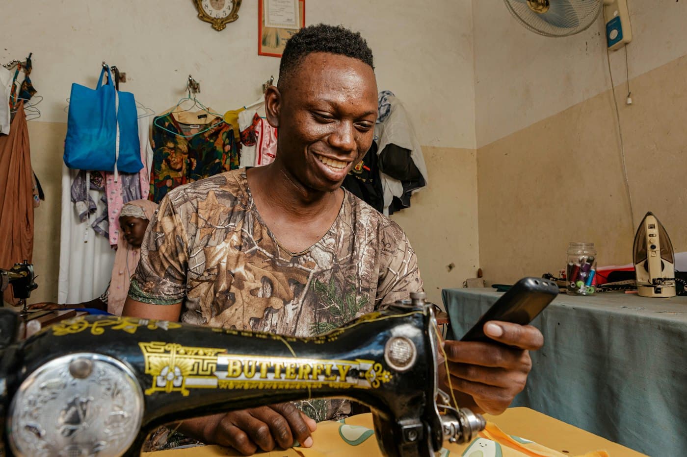 A tailor smiling as he works at his sewing machine