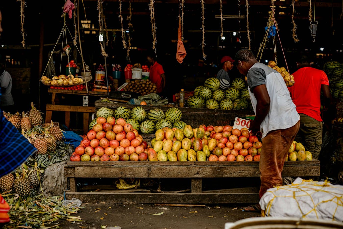 A fruit stall piled with melons, mangoes and oranges