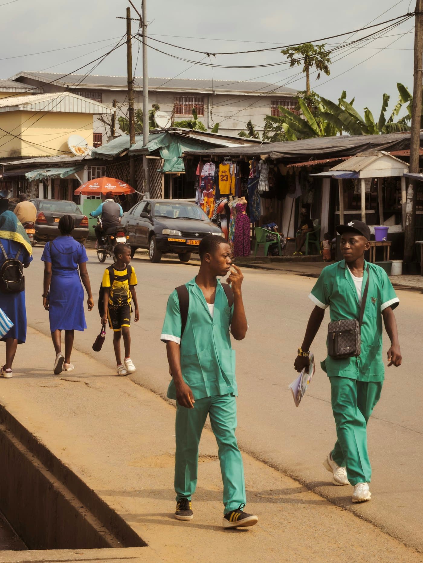 Health workers in scrubs walking along a busy street