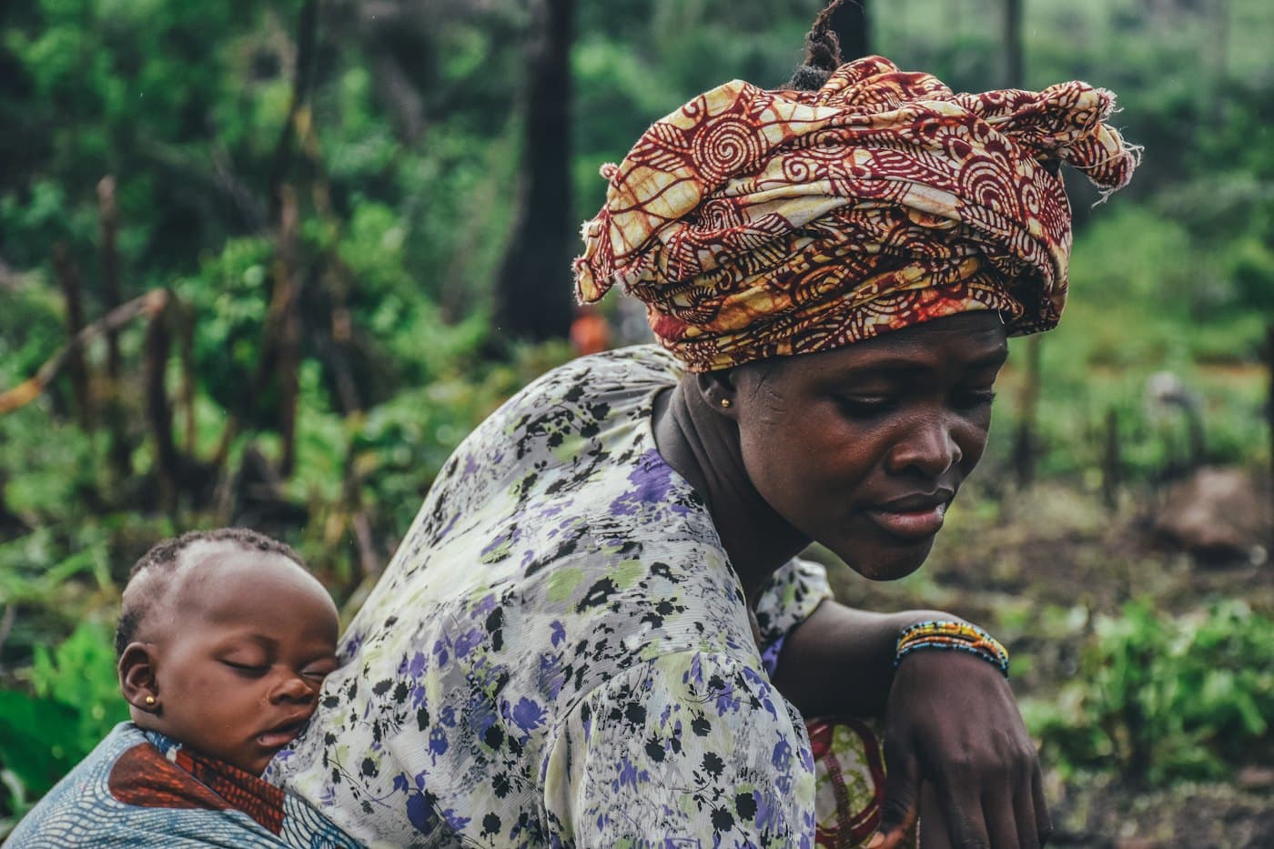 A woman working in a field with a baby tied on her back